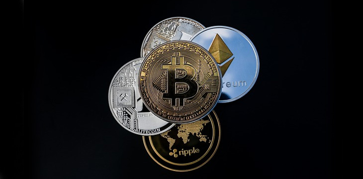Bitcoin (BTC) and other cryptocurrencies are illustrated as physical coins with dark background