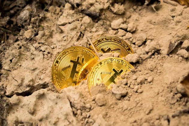 Bitcoin (BTC) is illustrated as physical gold coins and half-buried under the ground