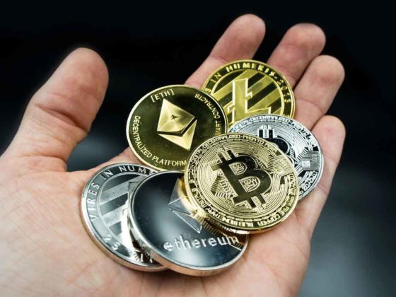A person is having physical illustrations of Bitcoin (BTC), Ethereum (ETH), and various cryptocurrencies in hand