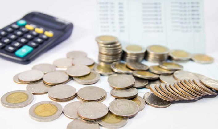 Stack of physical coins and calculator to illustrate compounded interest