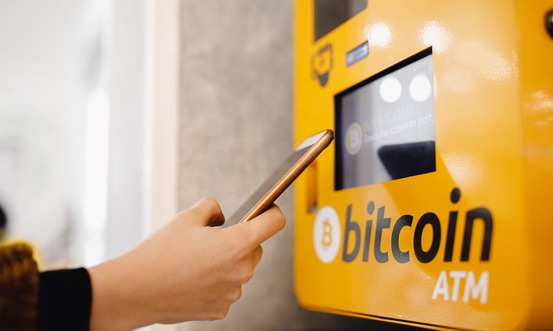 A person holding a phone in front of Bitcoin ATM machine to do some Bitcoin (BTC) transactions