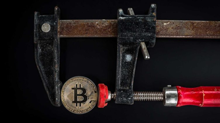 A Bitcoin is being measured to illustrate cryptocurrency balance