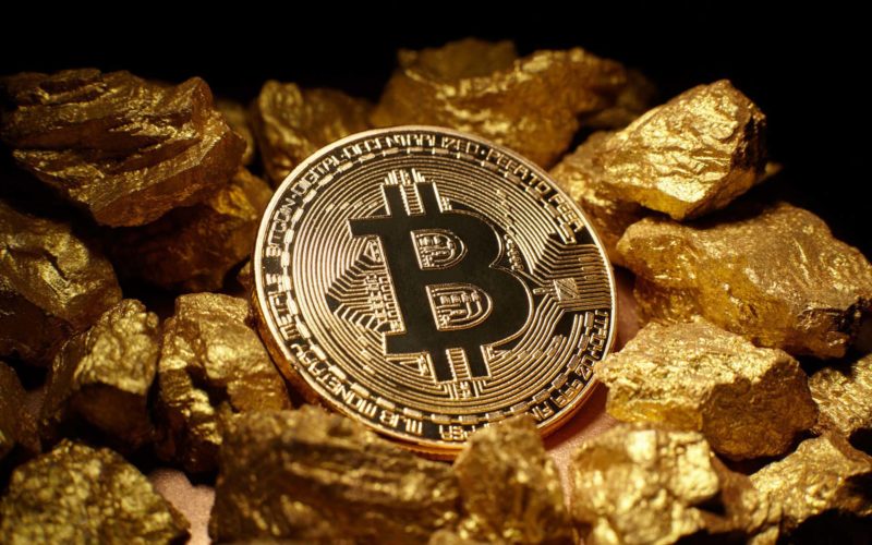 Physical BTC Bitcoin next to gold bars with dark shade