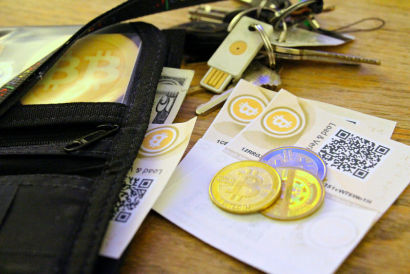 Physical bitcoins, keys, and QR codes on a wooden surface. 