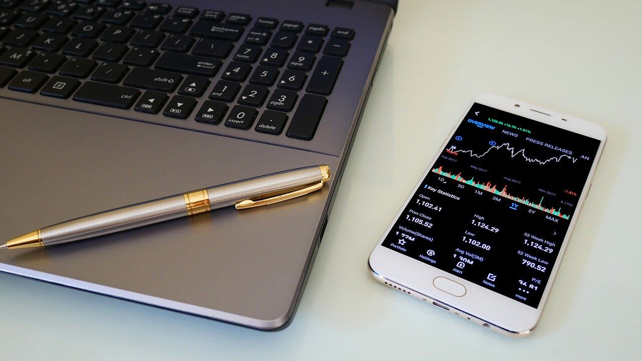A financial graph displayed on a phone next to a laptop computer to illustrate crypto investment