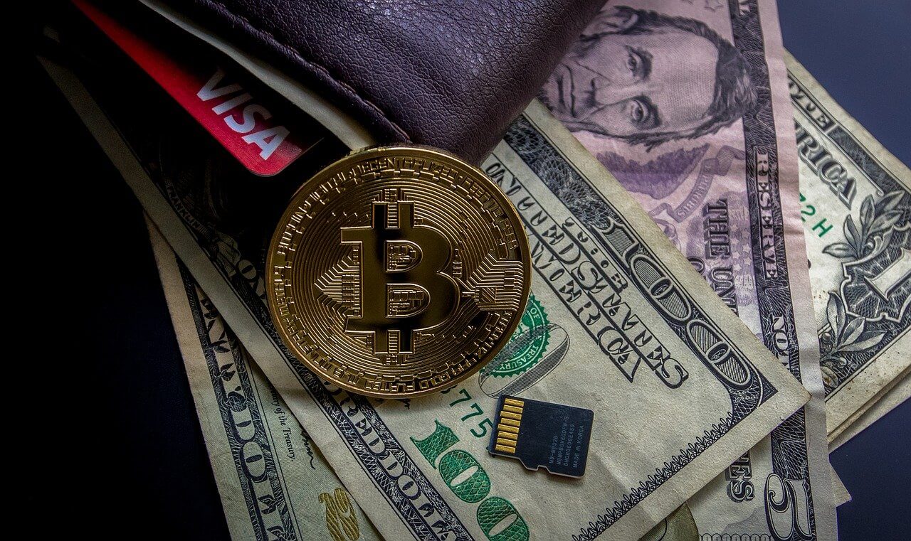 Image of golden bitcoin surrounded by a one hundred dollar bill