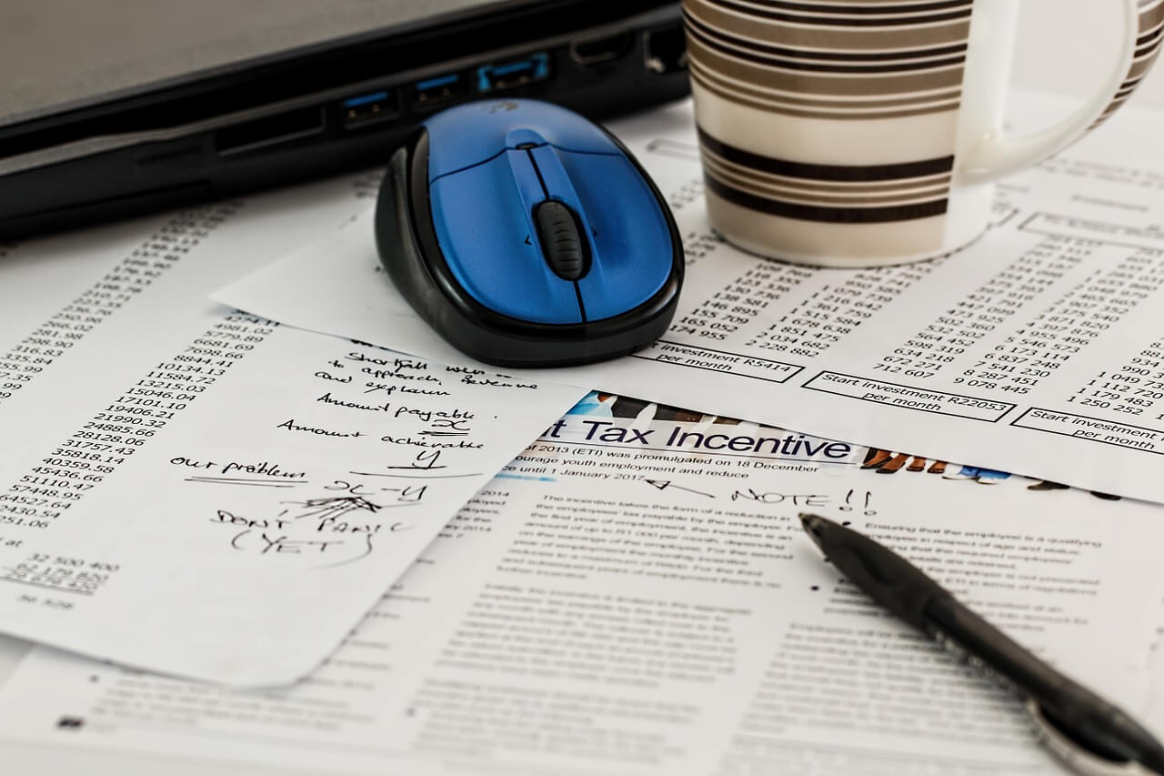 Image of paperwork with tax numbers along with a pen and coffee mug.