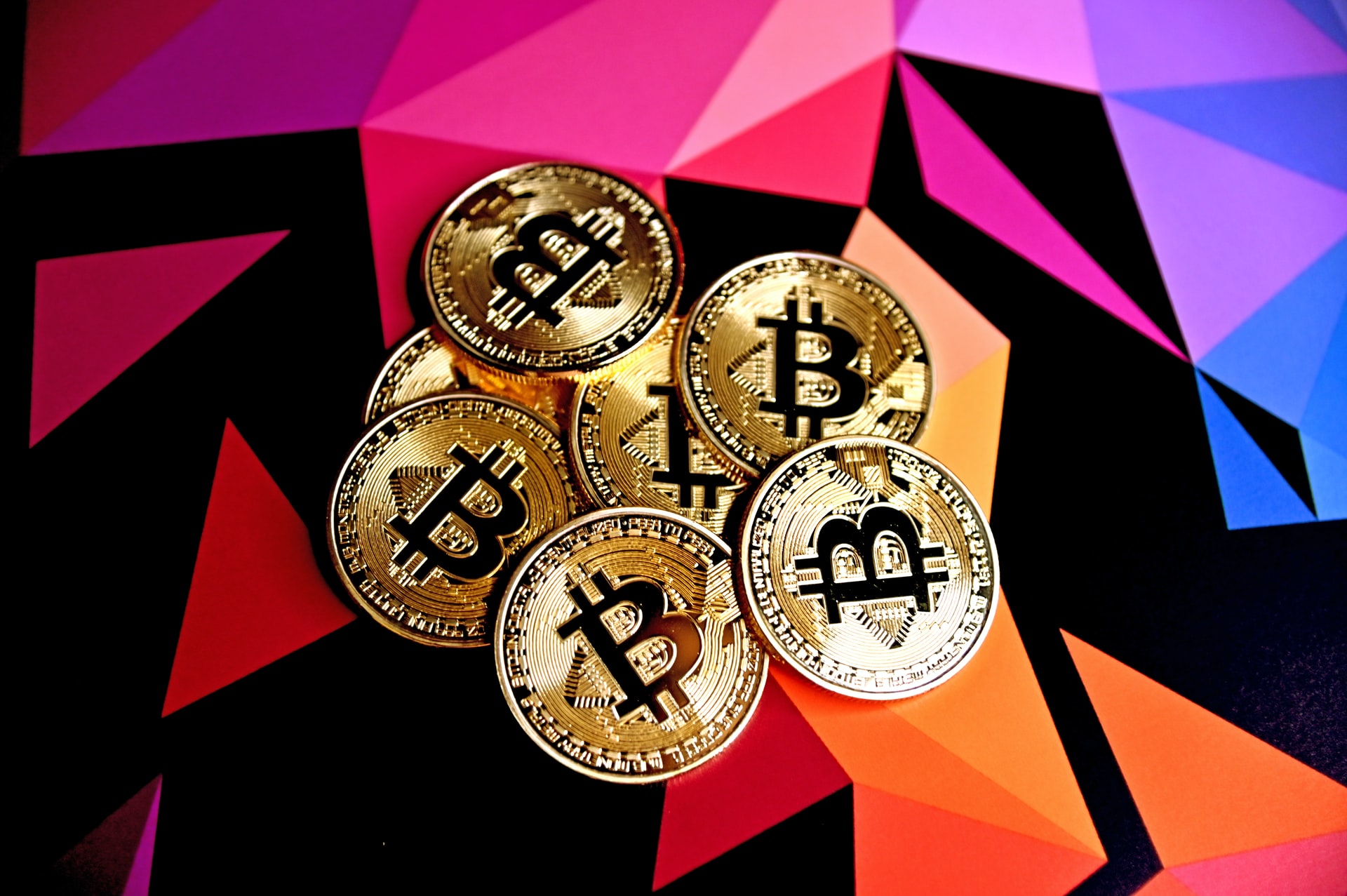 A pile of physical bitcoins placed on top of a colorful surface to illustrate the topic of what is cryptocurrency.