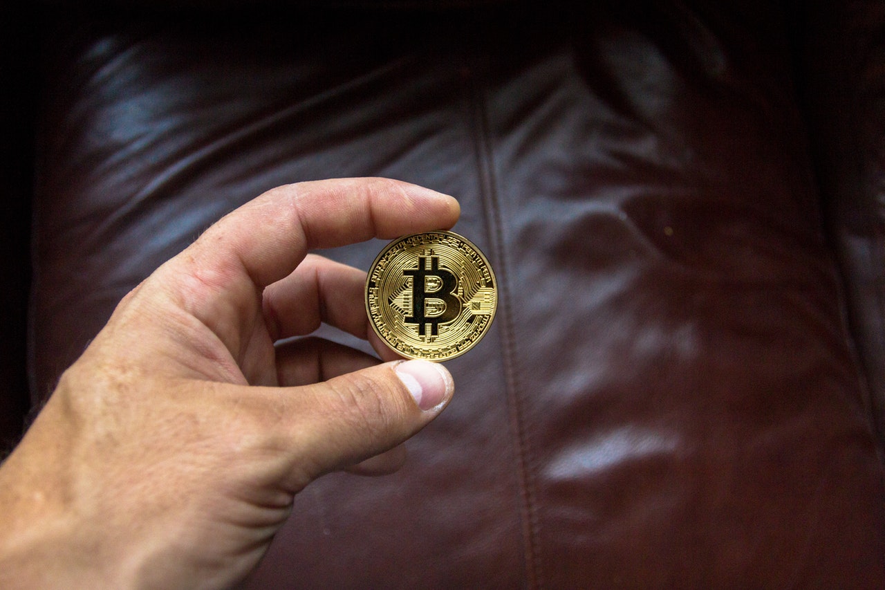 Image of a hand holding a physical bitcoin. 