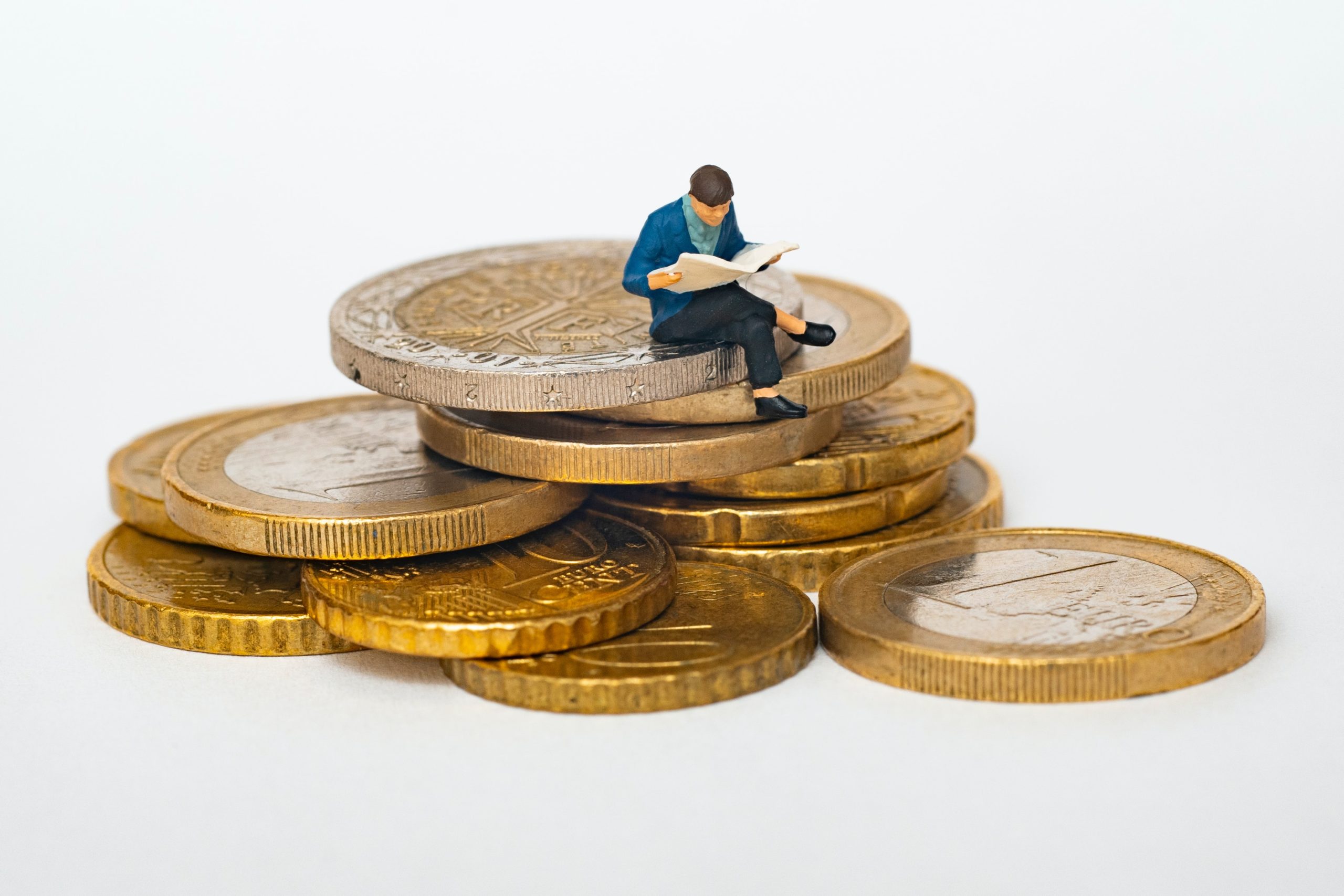 a miniature figure sitting on crypto coins.