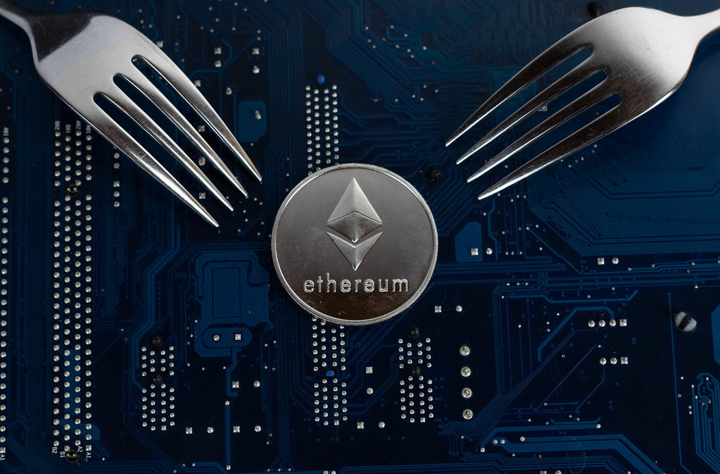 Two forks facing a physical Ethereum coin.