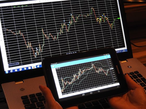 Photo of stock market chart on a computer screen and tablet screen.