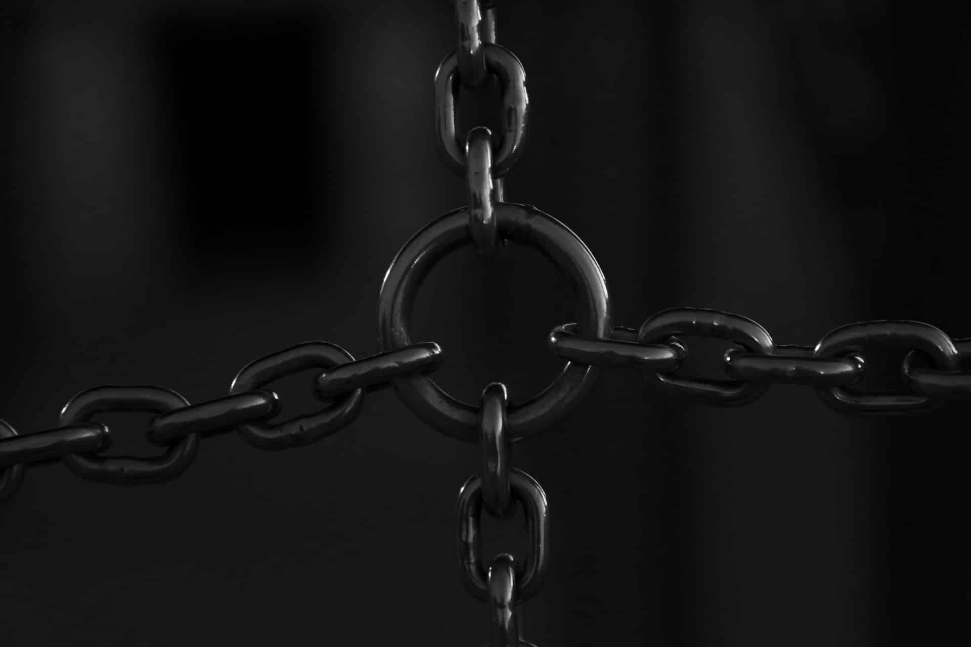 Photo of black interconnecting chains on a dark grey background.