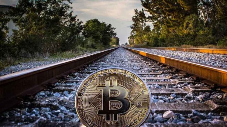 Bitcoin is illustrated as physical coin lying on railroad