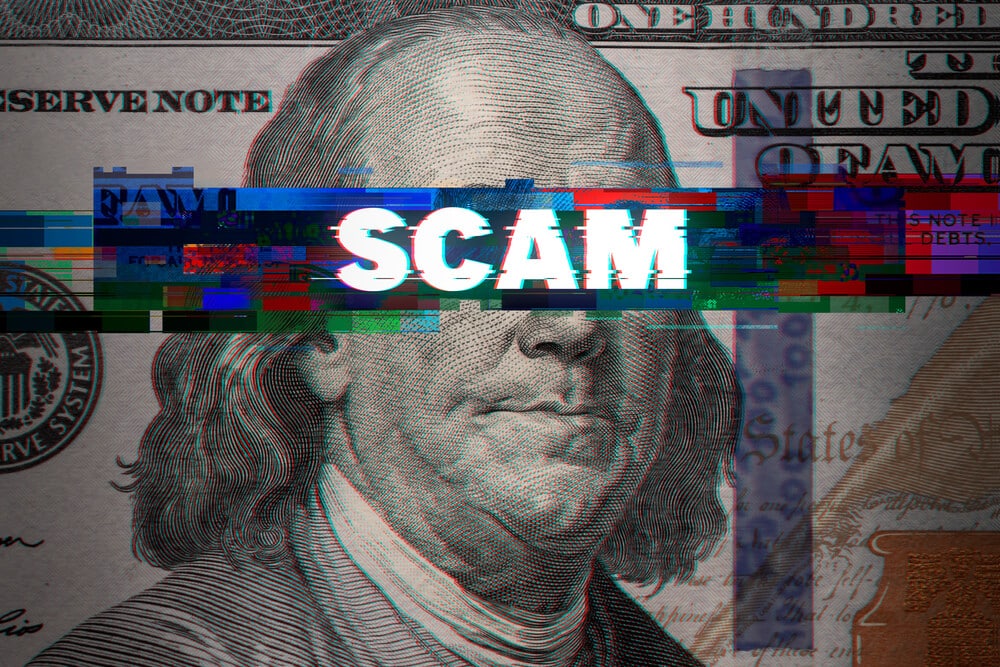 Photo of Benjamin Franklin dollar bill with the words scam written across his eyes.